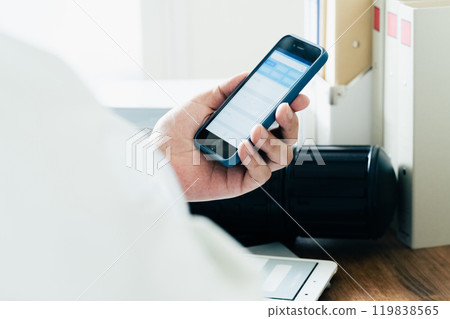 A man in work clothes operating a smartphone 119838565