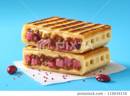 Two crispy, golden-brown sandwiches filled with savory meat, cheese, and red beans. Two crispy, golden-brown sandwiches filled with savory meat, cheese, and red beans. 119839158