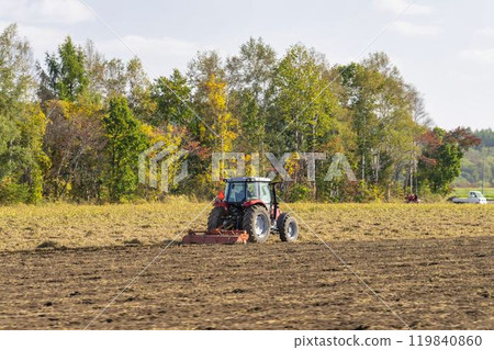 A red tractor plowing farmland in Obihiro, Hokkaido 119840860