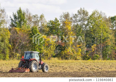 A red tractor plowing farmland in Obihiro, Hokkaido A red tractor plowing farmland in Obihiro, Hokkaido 119840861