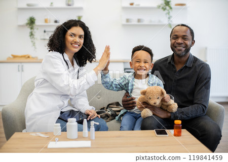 Friendly female doctor giving high five to happy child at home 119841459