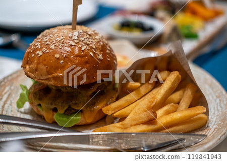 Close up of Burger with Cheese and Vegetable, and French Fries Close up of Burger with Cheese and Vegetable, and French Fries 119841943