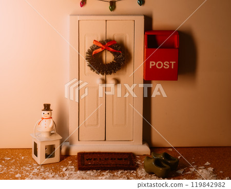 Front door decorated with a Christmas wreath and a small snowman 119842982