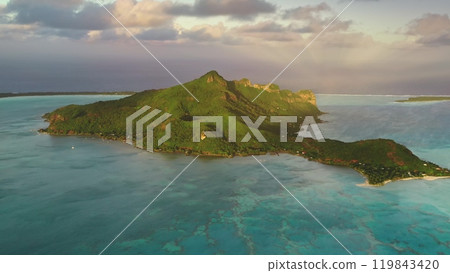 Aerial view Maupiti volcanic tropical island turquoise lagoon and coral reef barrier under colorful sunset sky. Beautiful wild nature landscape. Travel to French Polynesia exotic paradise. Drone shot 119843420