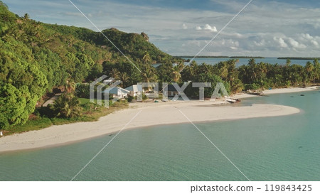 Aerial flight over bungalows houses on private small beach. Crystal water, white sand, palm trees, green hill landscape. Remote wild nature tropical island paradise, exotic vacation summer travel Aerial flight over bungalows houses on private small beach. Crystal water, white sand, palm trees, green hill landscape. Remote wild nature tropical island paradise, exotic vacation summer travel 119843425