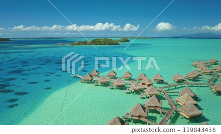 Overwater bungalows huts on tropical island in Bora Bora, crystal clear turquoise coral reef. French Polynesia popular tourist destination. Remote wild nature, exotic summer luxury travel. Aerial view 119843438