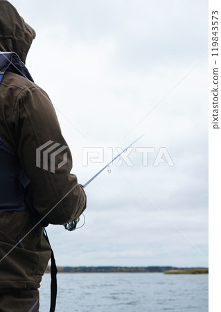 Silhouette of fisherman standing in the lake and catching the fish during cloudy weather Silhouette of fisherman standing in the lake and catching the fish during cloudy weather 119843573