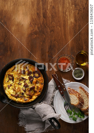 Healthy breakfast, omelette with fried seasonal forest mushrooms Chanterelles in frying pan on a wooden background with plate and cutlery, top view, copy space 119843607