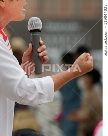 A candidate making a fist while holding a microphone during a campaign speech A candidate making a fist while holding a microphone during a campaign speech 119844025