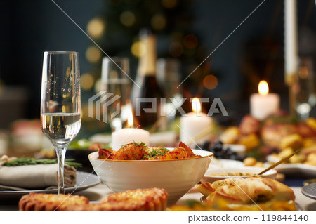 Background shot of baked potato wedges as side dish and champagne glass with sparkling drink served on festive dining table on Christmas Eve, copy space 119844140