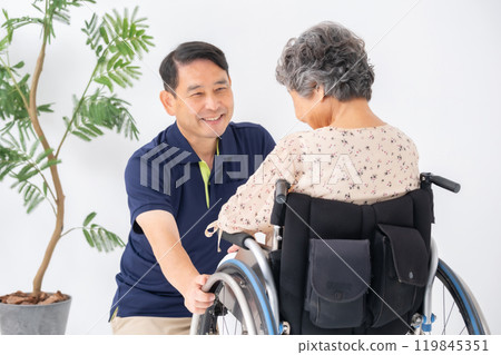 Senior woman in wheelchair and male caregiver Senior woman in wheelchair and male caregiver 119845351
