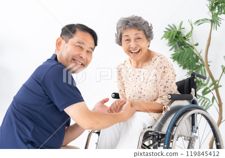 Senior woman in wheelchair and male caregiver Senior woman in wheelchair and male caregiver 119845412