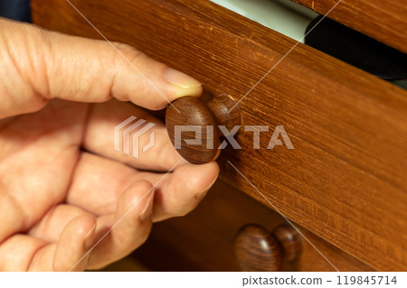 Open the drawer of a wooden chest of drawers Open the drawer of a wooden chest of drawers 119845714