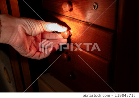 Opening a drawer in a dark room 119845715