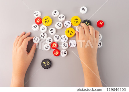 Child holding white cap with math problems, on gray background, educational flat lay for kids math learning, counting games, math activity for classroom, interactive math practice, 119846303