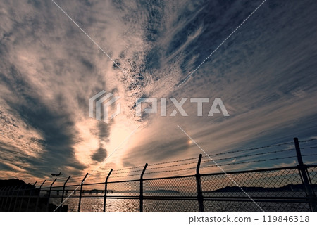 落日和飛機降落照亮的雲彩 119846318