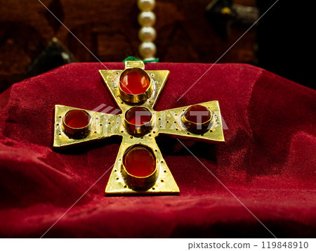 close up shot of golden jewel pendant ancient medieval set with red ruby gems representing a cross close up shot of golden jewel pendant ancient medieval set with red ruby gems representing a cross 119848910
