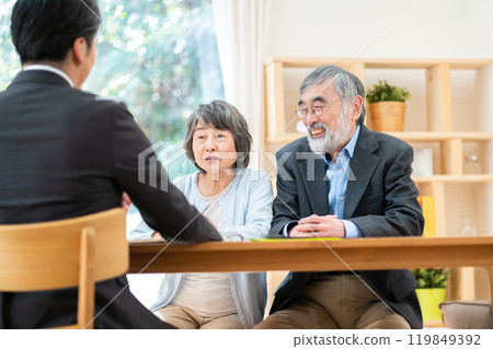 A salesman explaining to a senior couple: A senior couple consulting about inheritance 119849392