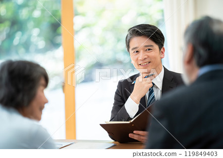 A salesman explaining to a senior couple: A senior couple consulting about inheritance 119849403