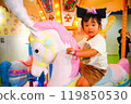 A girl riding a merry-go-round 119850530