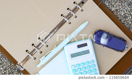 Model car a pen and a calculator are on notebook with blur background. Planning of saving for buying car, car loan and car insurance concept. 119850684