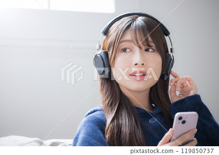 戴著耳機聽音樂的歌唱年輕女子的特寫圖像，有複製空間 119850737