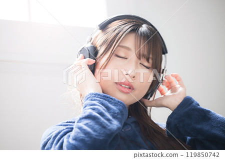 Close-up image of a young woman wearing headphones and singing listening to music 119850742