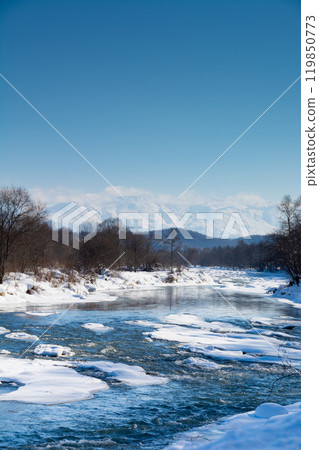 Winter riverbanks, snowy mountains and blue sky Tokachidake mountain range Winter riverbanks, snowy mountains and blue sky Tokachidake mountain range 119850773