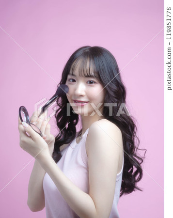 A woman applying makeup with cosmetics 119851778