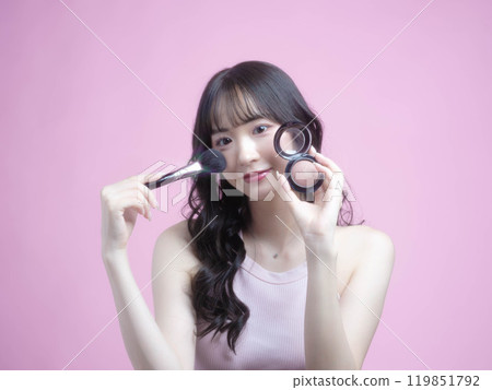 A woman applying makeup with cosmetics 119851792