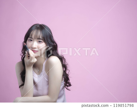 A woman applying makeup with cosmetics A woman applying makeup with cosmetics 119851798