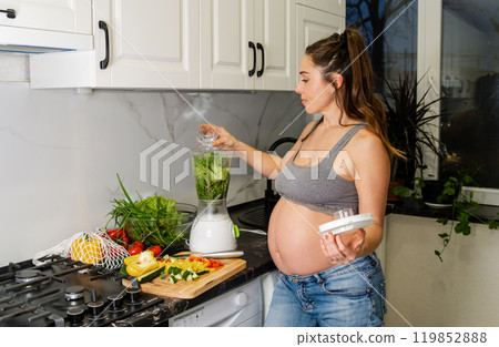 A young pregnant woman drinks a prepared vitamin smoothie A young pregnant woman drinks a prepared vitamin smoothie 119852888