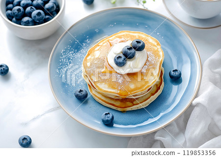 Top view on pancakes with berries, freshly baked crepes with whipped cream and blueberries, cup of coffee with milk, perfect breakfast, first morning meal 119853356
