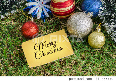 Top view of Merry Christmas text on yellow paper card with Christmas decoration background. 119853550