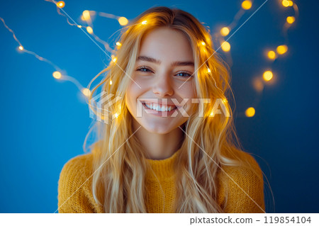 Happy young woman with glowing light strings around her head, a concept of mindfulness, meditation, creativity inspiration. Cozy home Christmas time, decorative Christmas twinkling string lights 119854104