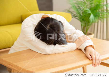 Middle-aged to senior woman collapses on table 119854127