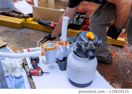 Maintenance worker installing swimming pool cleaning equipment sand filter system tank 119854235