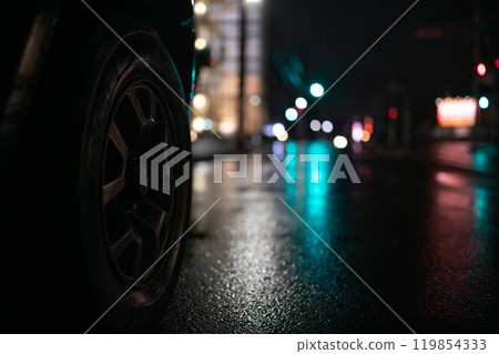 Rain-soaked intersection and car tires at night Rain-soaked intersection and car tires at night 119854333