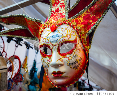 close-up of a red, white and gold mask for sale from the Venice carnival that recalls the figure of a jester close-up of a red, white and gold mask for sale from the Venice carnival that recalls the figure of a jester 119854405