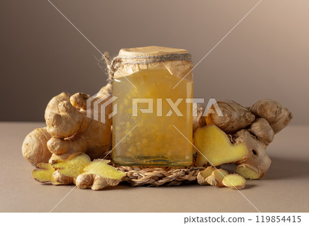 Ginger jam in small square jar and fresh ginger. 119854415