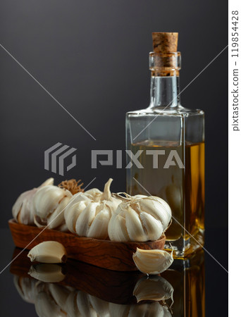 Garlic bulbs and bottle of vegetable oil on a black background. Garlic bulbs and bottle of vegetable oil on a black background. 119854428