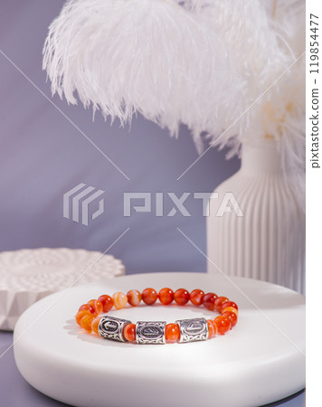 Woman's wrist wearing orange agate bracelet, isolated on white background. Woman's wrist wearing orange agate bracelet, isolated on white background. 119854477