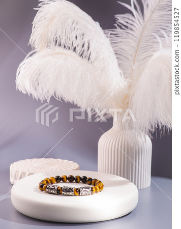 White bracelet made of natural kohalong stone on a woman's hand against a blue sky. Texture of pearl agate close-up. High quality photo 119854527