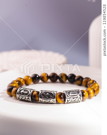 White bracelet made of natural kohalong stone on a woman's hand against a blue sky. Texture of pearl agate close-up. High quality photo 119854528