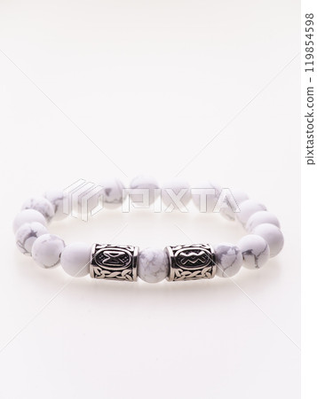 A charming double bracelet in shades of pink, made from natural stone and set against a gray background. The heart charm with cubic zirconia stands out in this close-up top view A charming double bracelet in shades of pink, made from natural stone and set against a gray background. The heart charm with cubic zirconia stands out in this close-up top view 119854598