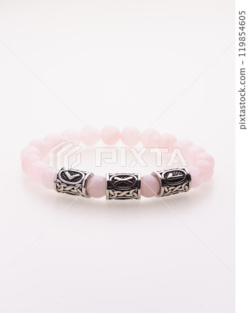 A charming double bracelet in shades of pink, made from natural stone and set against a gray background. The heart charm with cubic zirconia stands out in this close-up top view 119854605