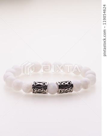 A charming double bracelet in shades of pink, made from natural stone and set against a gray background. The heart charm with cubic zirconia stands out in this close-up top view 119854624