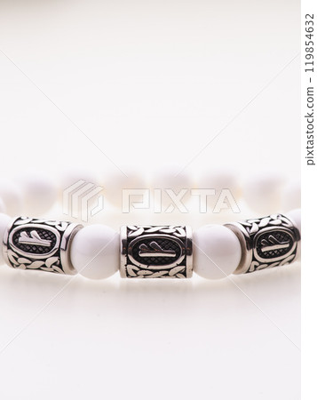 A charming double bracelet in shades of pink, made from natural stone and set against a gray background. The heart charm with cubic zirconia stands out in this close-up top view 119854632