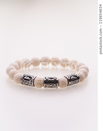 A charming double bracelet in shades of pink, made from natural stone and set against a gray background. The heart charm with cubic zirconia stands out in this close-up top view 119854654