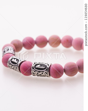 A charming double bracelet in shades of pink, made from natural stone and set against a gray background. The heart charm with cubic zirconia stands out in this close-up top view 119854680